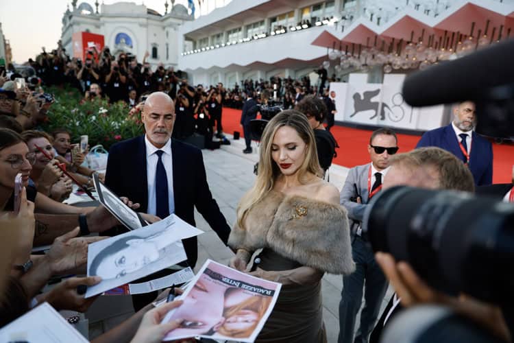 Angelina Jolie se arrodilla ante un fan en el Festival de Cine de Venecia