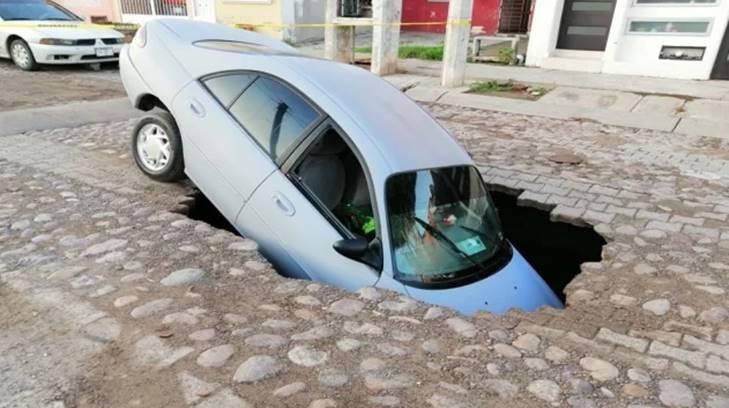 Conductor en Sinaloa pasa gran susto cuando se le abre la tierra y cae; sacan auto con grúa