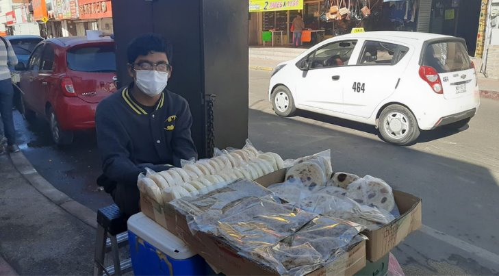 Joven vende productos comestibles en el centro para pagar su escuela